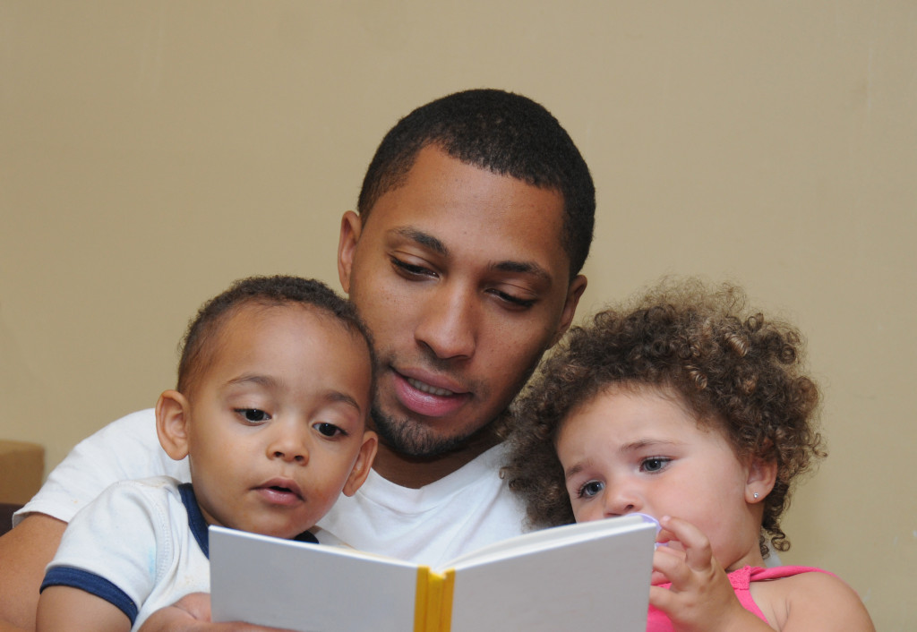 children reading book with father