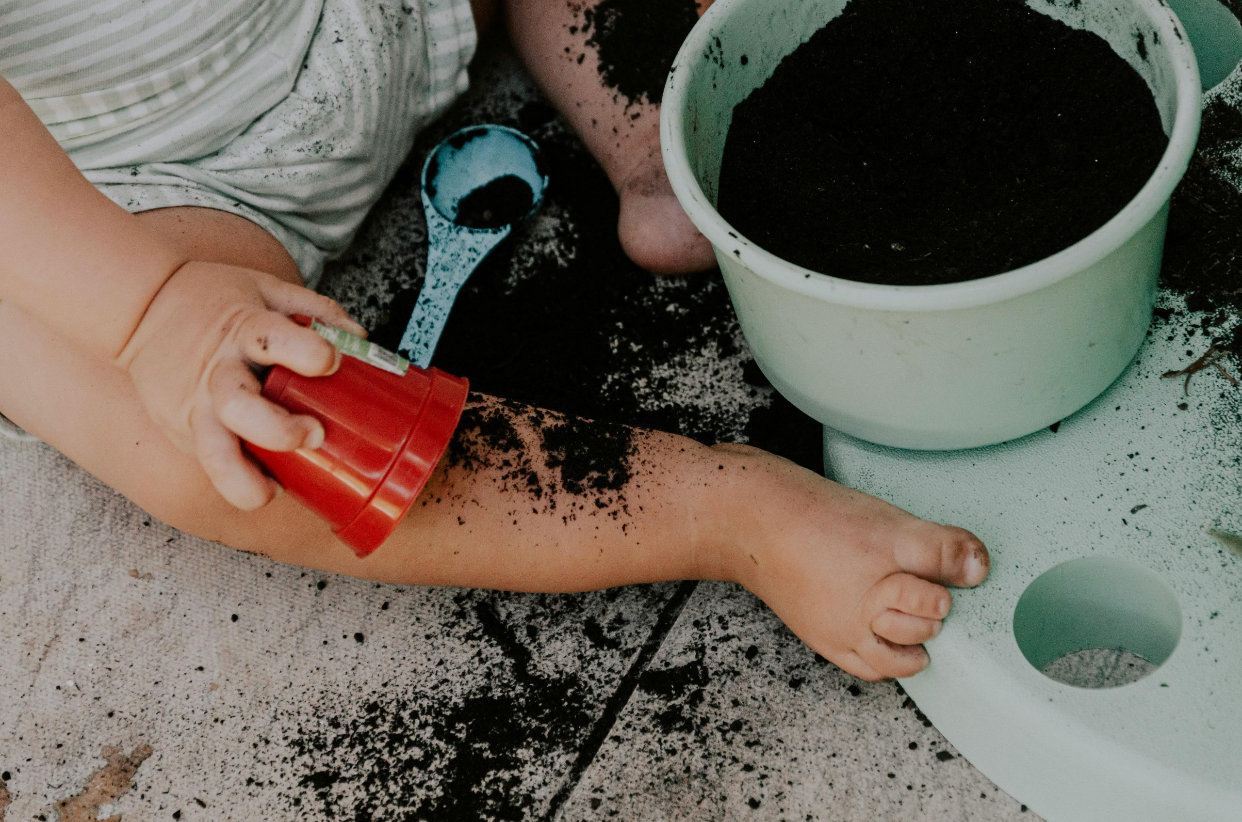 toddler sitting and playing with soil