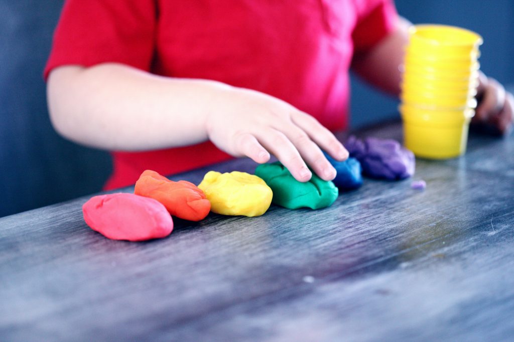 close-up of a child's hand touching colorful clay
