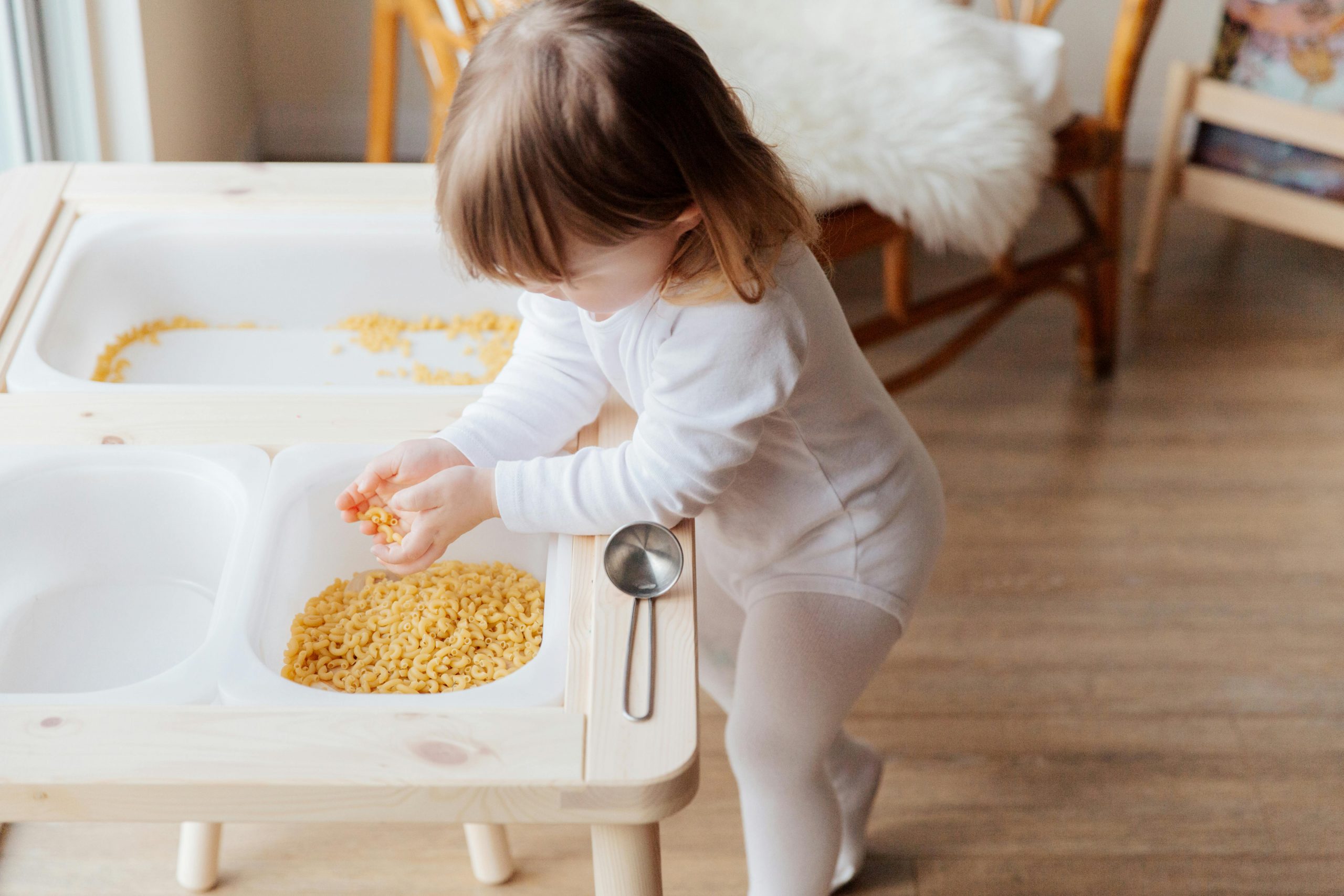 young girl scooping macaroni with both hands